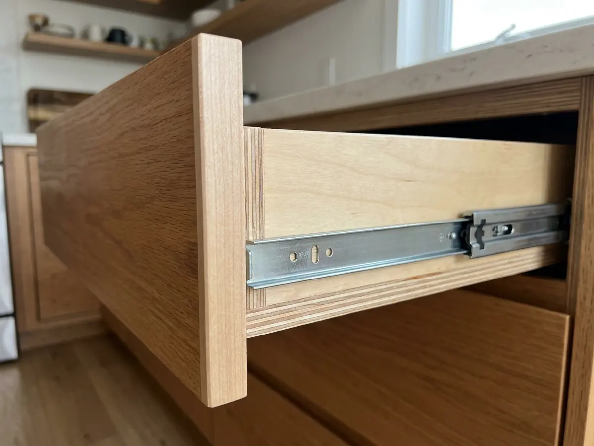 Open cabinet drawer showing plywood box and metal drawer slide